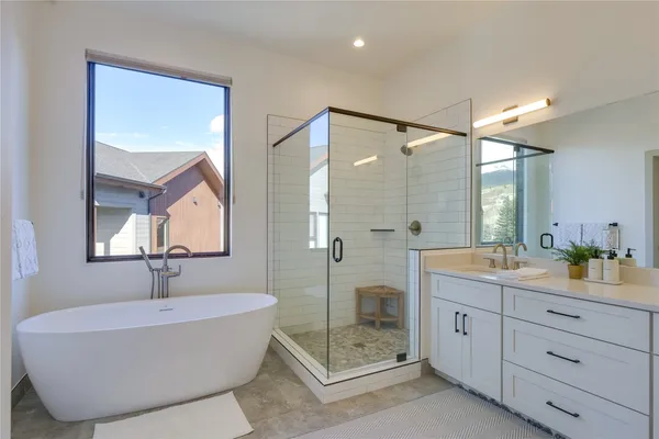 a bathroom with a tub sink shower and mirror