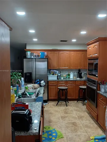 a kitchen with stainless steel appliances kitchen island granite countertop a refrigerator and a stove