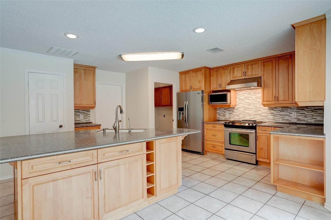 7604 Napier Trail Austin, TX 78729 - Photo 12 of 27 a kitchen with stainless steel appliances granite countertop a sink and cabinets
