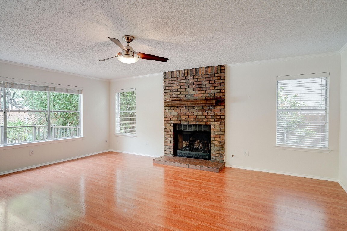 7604 Napier Trail Austin, TX 78729 - Photo 10 of 27 a view of an empty room with wooden floor fireplace and a window