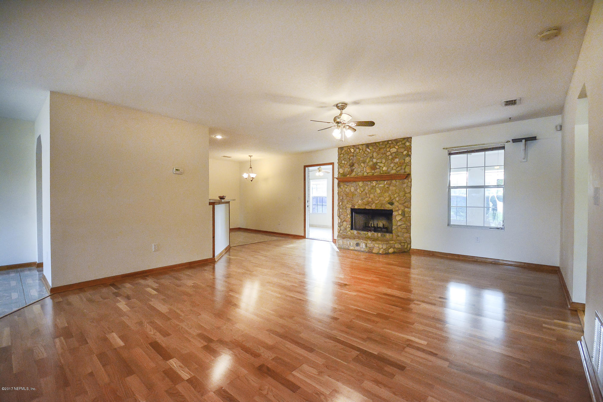 4822 Ricker Road Jacksonville, FL 32210 - Photo 11 of 50 an empty room with wooden floor fireplace and windows