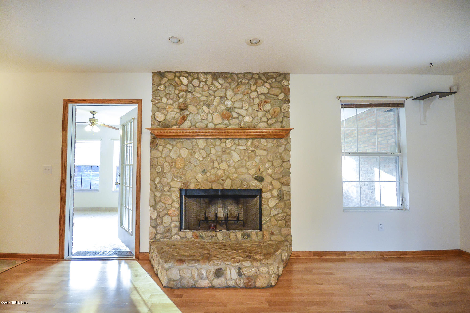 4822 Ricker Road Jacksonville, FL 32210 - Photo 13 of 50 an empty room with wooden floor fireplace and windows