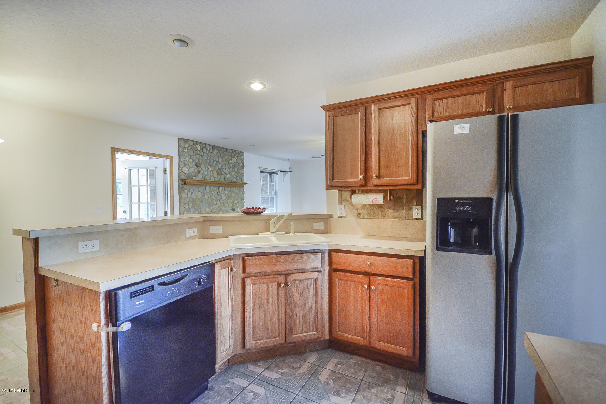 4822 Ricker Road Jacksonville, FL 32210 - Photo 17 of 50 a kitchen with a sink a refrigerator and cabinets