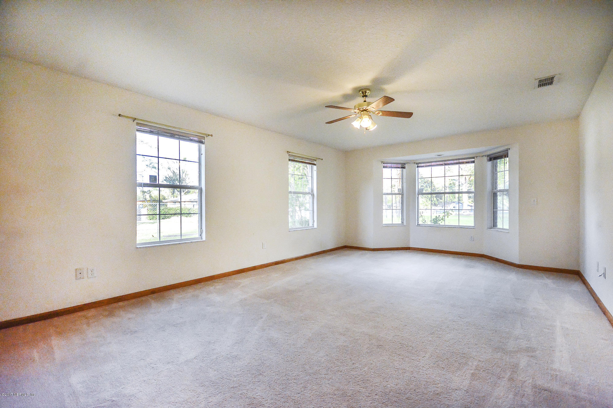 4822 Ricker Road Jacksonville, FL 32210 - Photo 27 of 50 an empty room with chandelier fan and windows