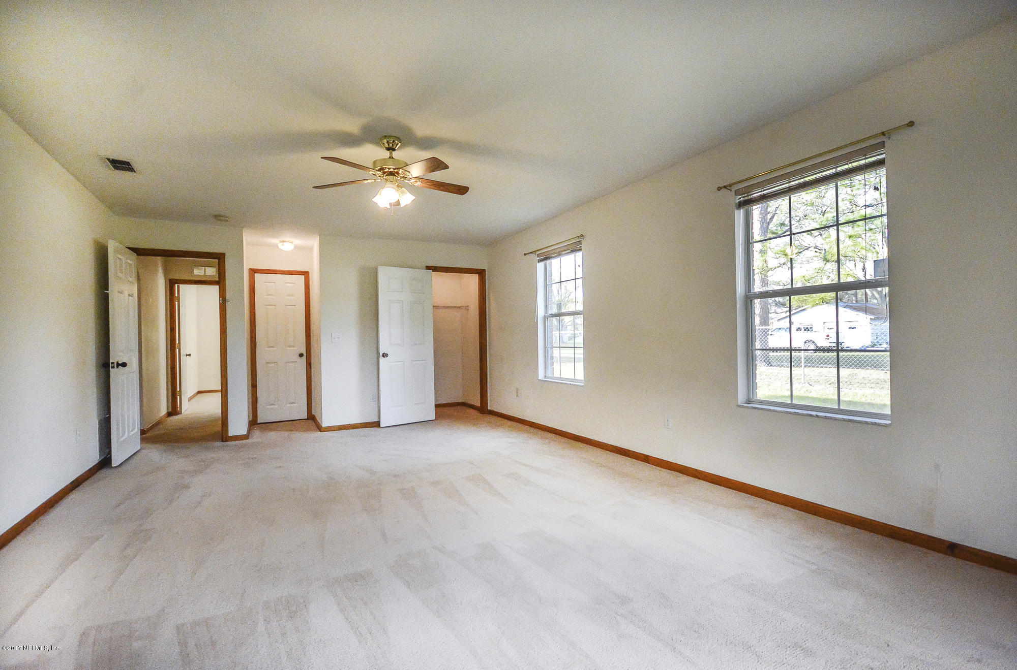 4822 Ricker Road Jacksonville, FL 32210 - Photo 28 of 50 an empty room with chandelier fan and windows