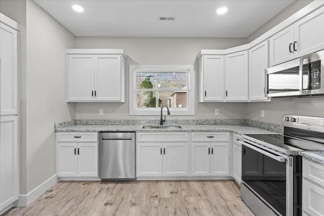 a kitchen with stainless steel appliances granite countertop a stove a sink and a microwave
