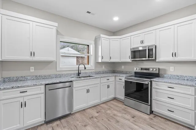a kitchen with granite countertop white cabinets white stainless steel appliances and a sink