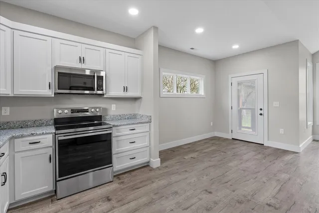 a kitchen with granite countertop a stove a microwave and a sink