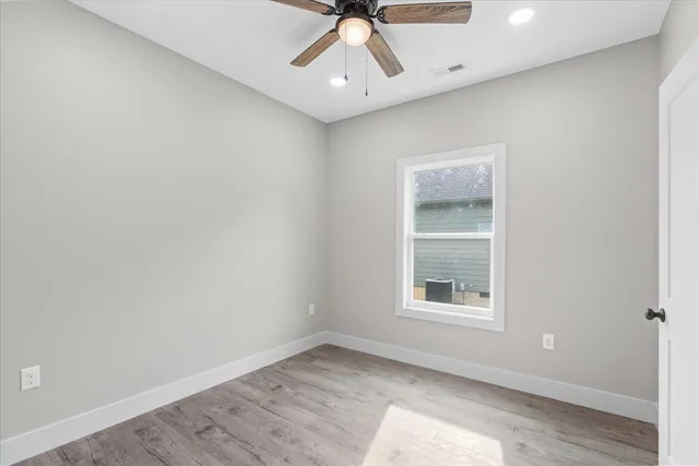 an empty room with a window and a ceiling fan