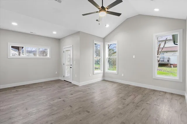 a view of an empty room with a window and wooden floor