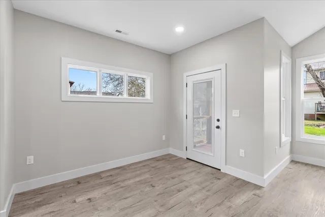 an empty room with wooden floor and windows