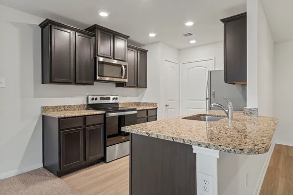 a kitchen with kitchen island granite countertop stainless steel appliances stove microwave and sink