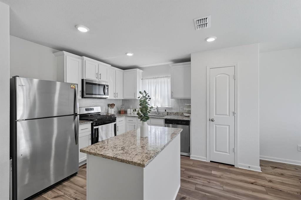 13511 Mineral Road Ponder, TX 76259 - Photo 17 of 40 a kitchen with kitchen island white cabinets appliances and wooden floor