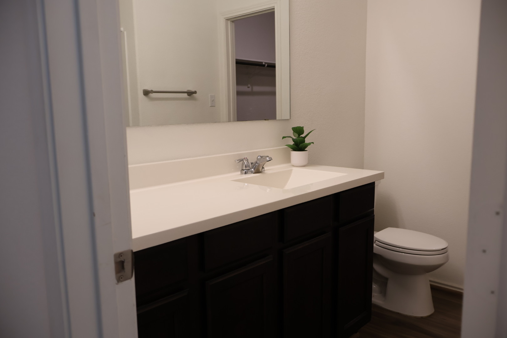 117 Galaxy Way Jarrell, TX 76537 - Photo 10 of 17 Bathroom featuring a vanity with a white countertop and an integrated sink, dark wood-finish cabinetry, a chrome faucet, and a wall-mounted mirror
