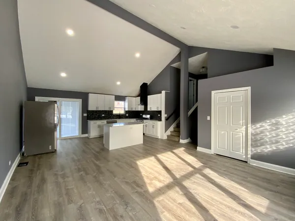 a large kitchen with stainless steel appliances kitchen island granite countertop a refrigerator and a stove top oven