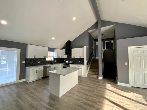 a large kitchen with stainless steel appliances kitchen island granite countertop a large counter top and a stove top oven