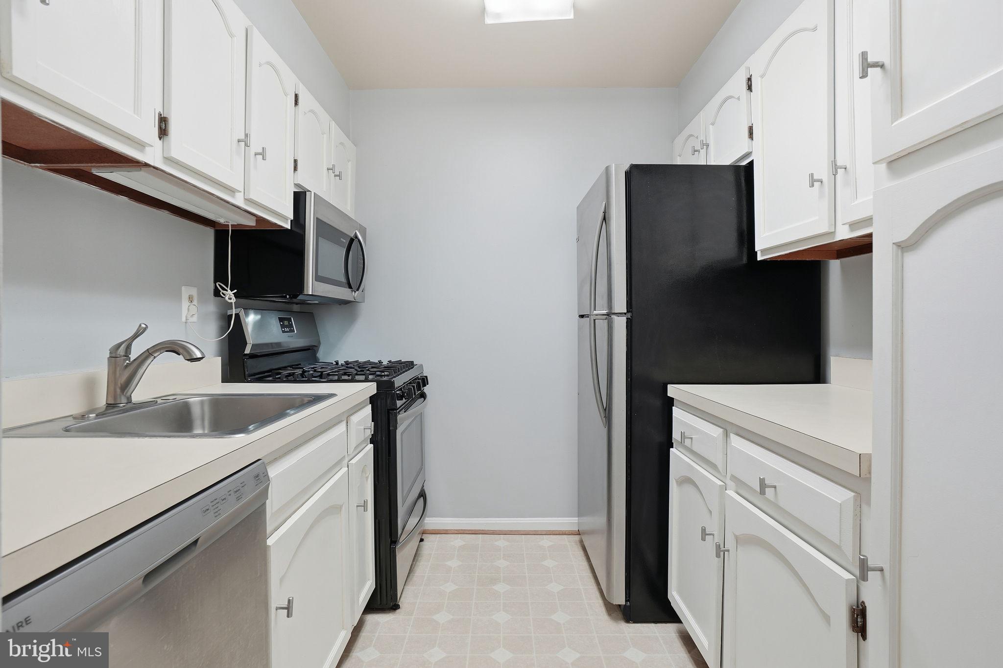 5902 Cove Landing Road, Unit 203 Burke, VA 22015 - Photo 6 of 25 a kitchen with white cabinets and stainless steel appliances