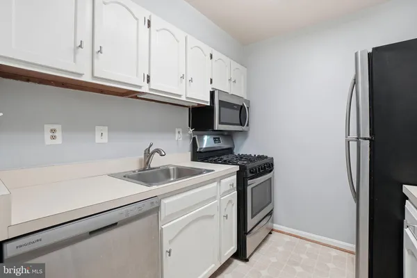 a kitchen with stainless steel appliances granite countertop white cabinets a refrigerator and a sink