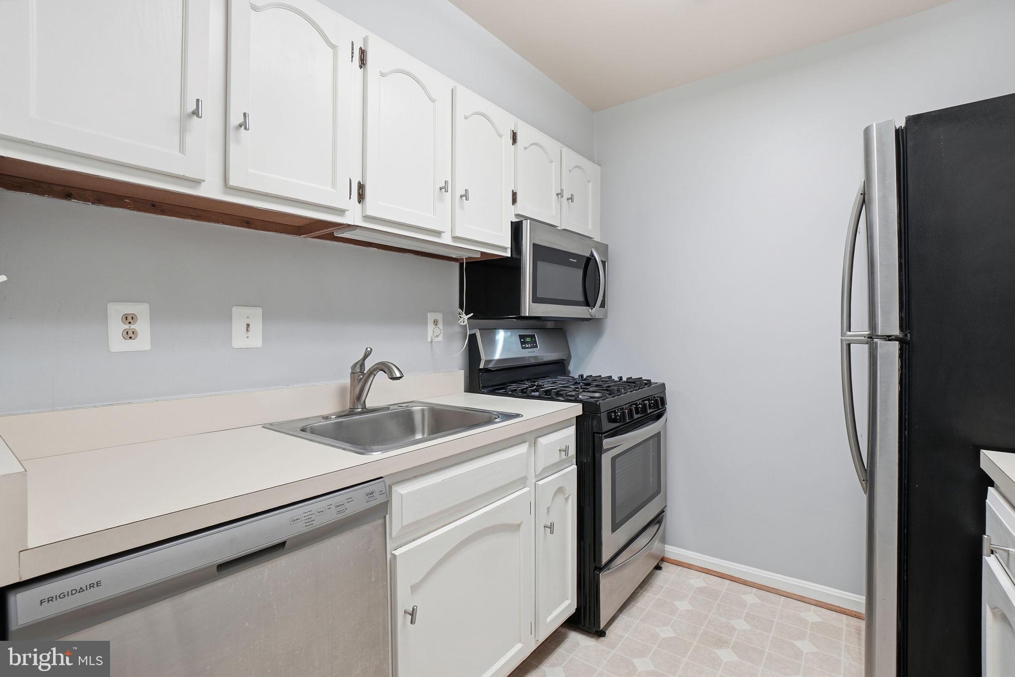 5902 Cove Landing Road, Unit 203 Burke, VA 22015 - Photo 7 of 25 a kitchen with stainless steel appliances granite countertop white cabinets a refrigerator and a sink