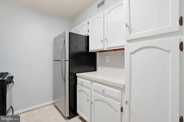 a kitchen with white cabinets and refrigerator