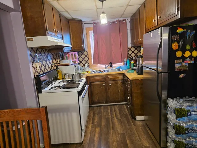 a kitchen with stainless steel appliances granite countertop a refrigerator a stove and a wooden floors