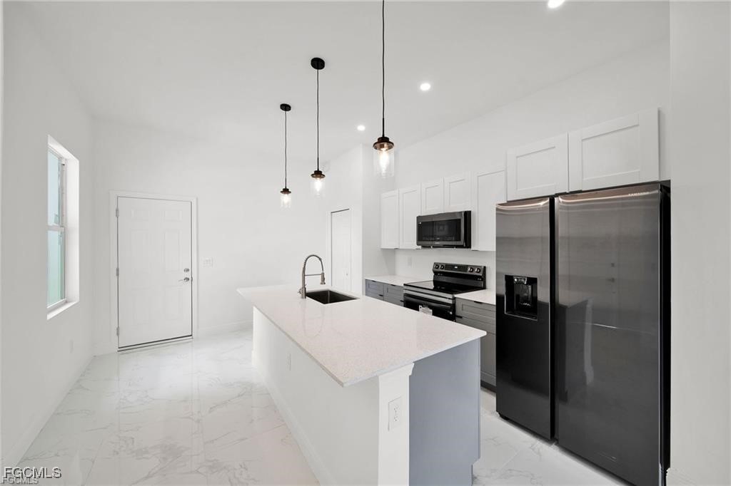 4768 Nelson Drive Lehigh Acres, FL 33973 - Photo 11 of 30 a kitchen with stainless steel appliances a refrigerator sink and stove
