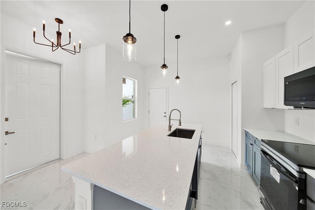 4768 Nelson Drive Lehigh Acres, FL 33973 - Photo 12 of 30 a kitchen with stainless steel appliances granite countertop a sink a stove and a refrigerator