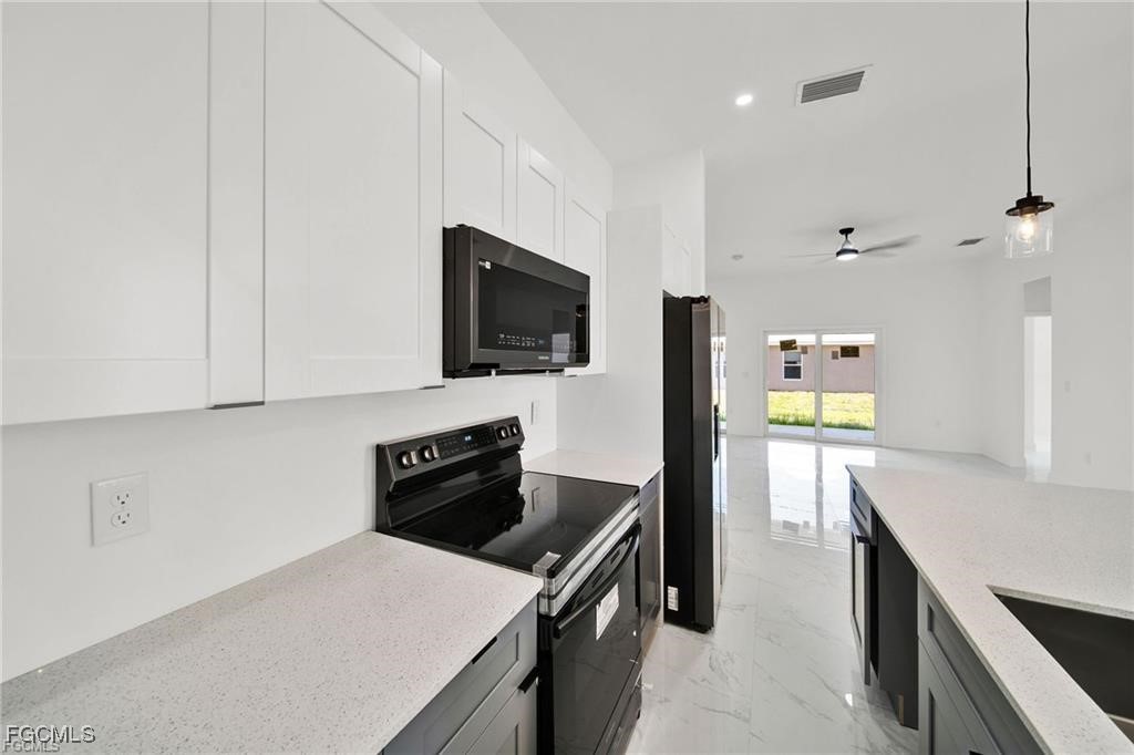 4768 Nelson Drive Lehigh Acres, FL 33973 - Photo 13 of 30 a kitchen with a sink a stove top oven a counter space and cabinets