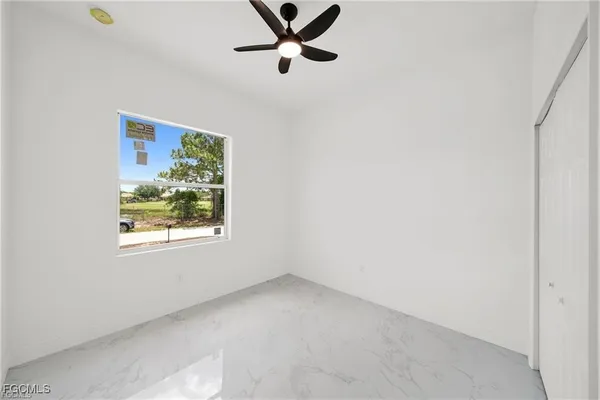 an empty room with windows and fan