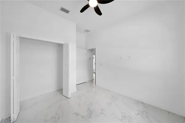 an empty room with ceiling fan and window
