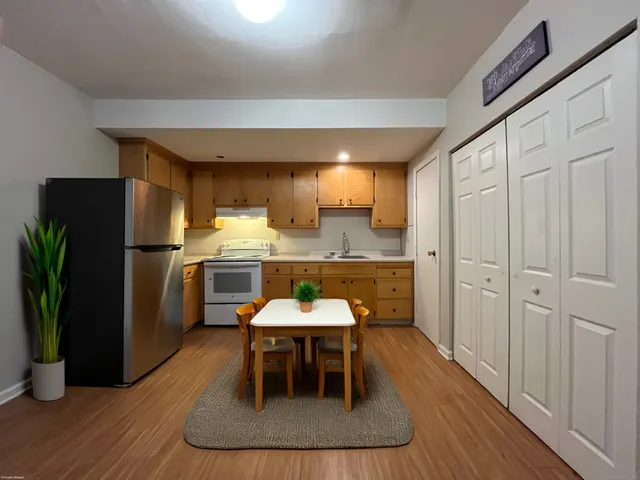 a kitchen with stainless steel appliances granite countertop a refrigerator a sink a stove and white cabinets with wooden floor