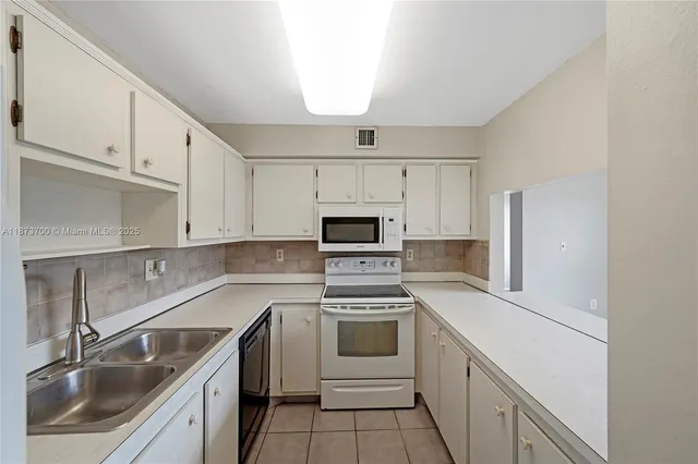 a kitchen with white cabinets sink and stainless steel appliances