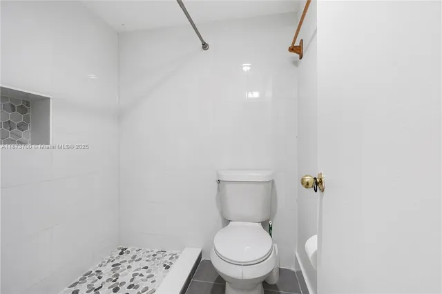 a white toilet sitting next to a shower