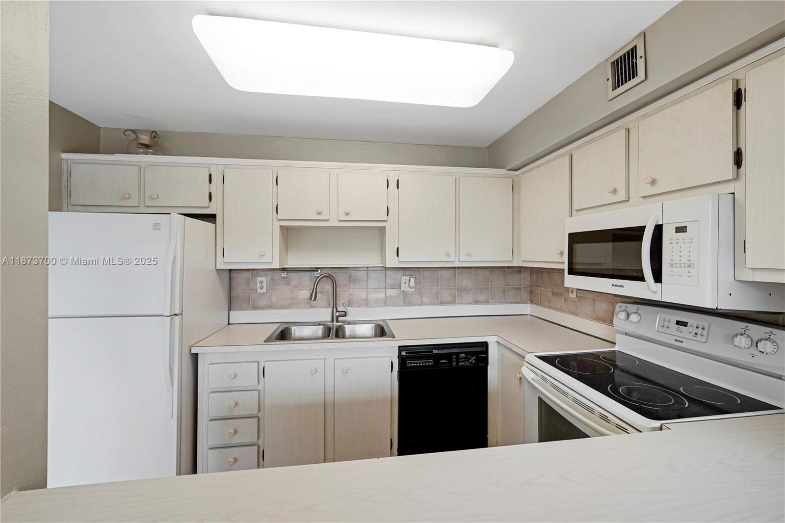 9491 Evergreen Place, Unit 207 Davie, FL 33324 - Photo 10 of 42 a kitchen with cabinets appliances a sink and a counter top
