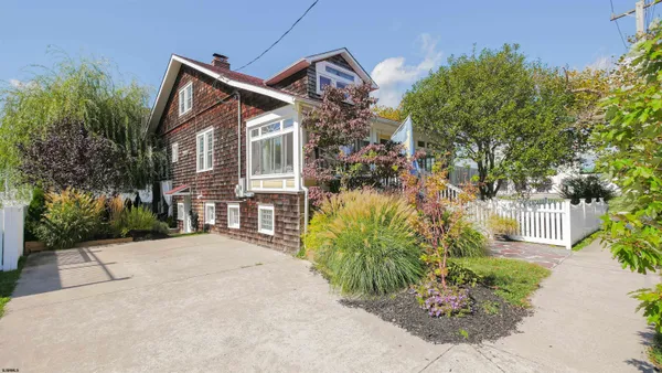 a front view of a house with a yard and potted plants