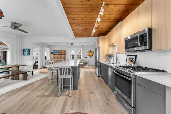 a kitchen with stainless steel appliances granite countertop a stove top oven a sink dishwasher a dining table and chairs with wooden floor