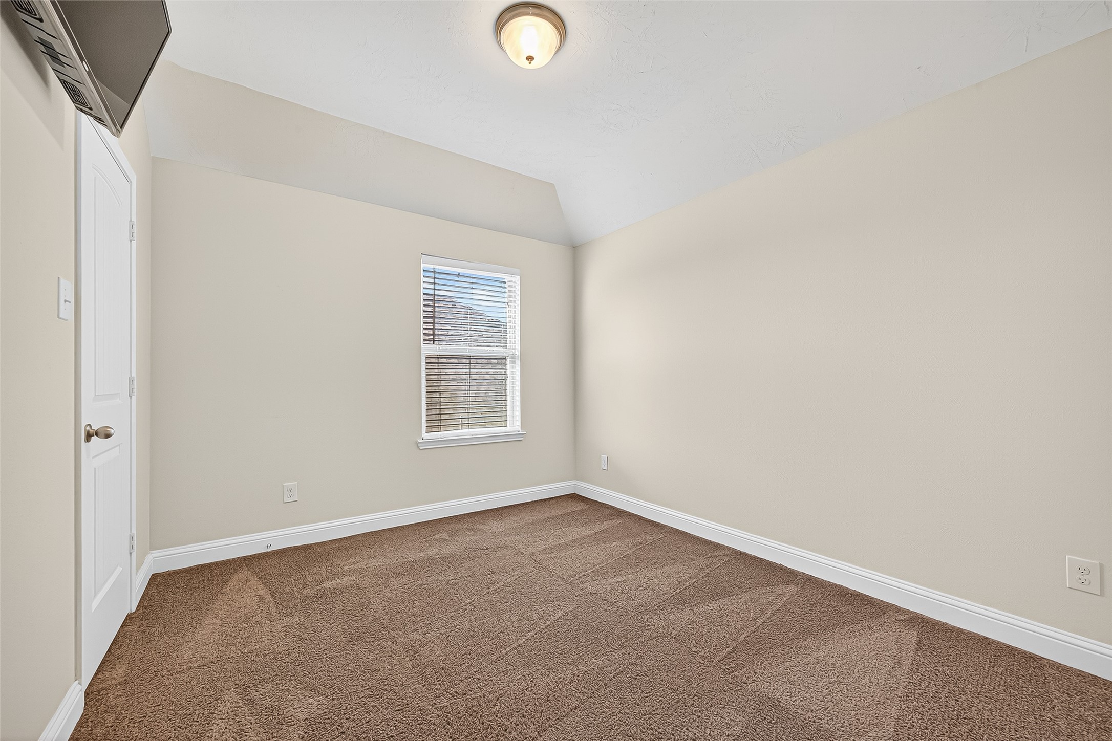 8107 Lockridge Terrace Lane Cypress, TX 77433 - Photo 43 of 50 This upstairs secondary bedroom offers a quiet retreat with its elevated ceilings, fresh neutral palette, and elegant wood-look flooring. A large window fills the room with natural light, while the layout easily accommodates a bed, desk, or reading nook—perfect for growing needs or guest stays.