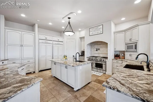 a kitchen with stainless steel appliances granite countertop a stove top oven a sink a dining table and chairs with wooden floor