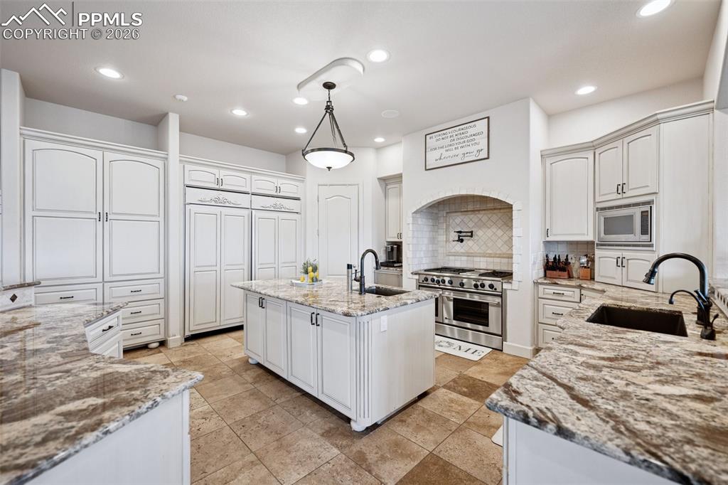 5039 Stonehill Road Colorado Springs, CO 80918 - Photo 16 of 50 a kitchen with stainless steel appliances granite countertop a stove top oven a sink a dining table and chairs with wooden floor