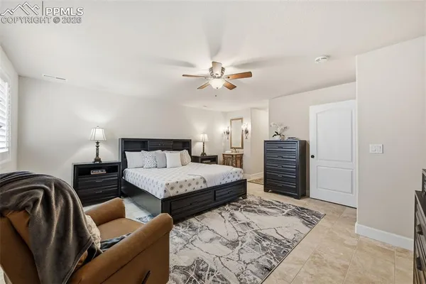 a spacious bedroom with a bed a couch and a chandelier