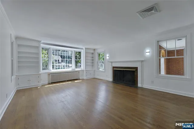 an empty room with windows fireplace and wooden floor