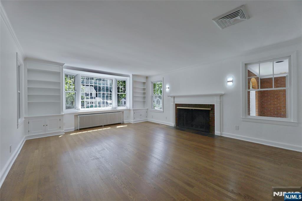 55 Forest Road Demarest, NJ 07627 - Photo 5 of 27 an empty room with windows fireplace and wooden floor