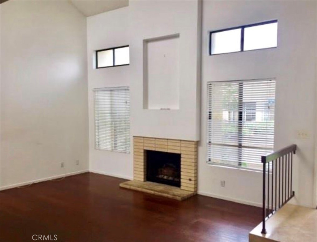 17 Grenache, Unit 72 Irvine, CA 92614 - Photo 4 of 20 an empty room with wooden floor a fireplace and windows