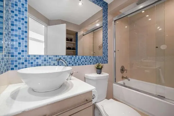 a bathroom with a sink a toilet a mirror and bathtub