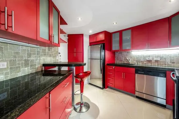 a kitchen with stainless steel appliances granite countertop a red stove top oven a sink and dishwasher