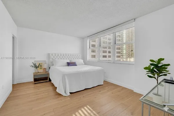 a bedroom with a bed potted plant on table and a window