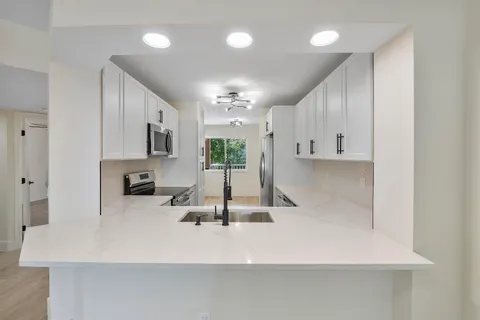 a view of a kitchen with kitchen island a sink stainless steel appliances and cabinets