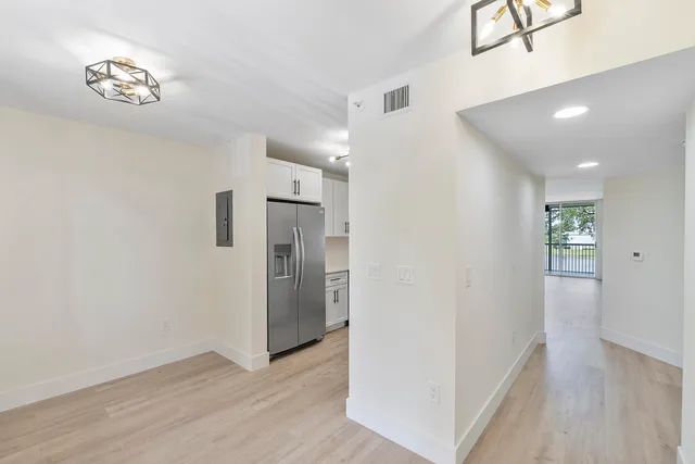 a view of a hallway with wooden floor and a kitchen space
