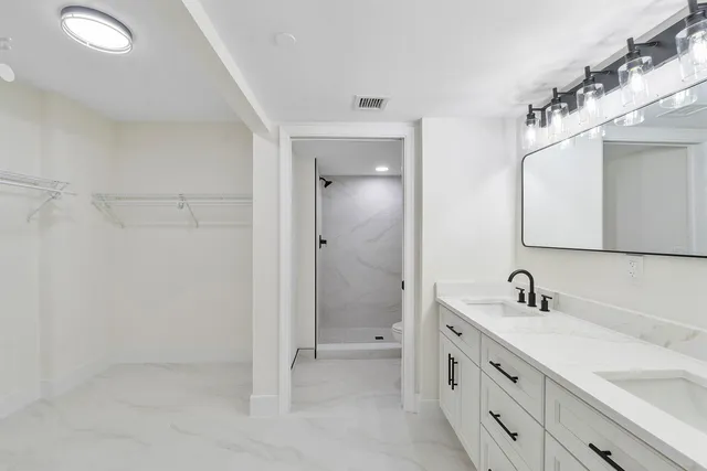 a bathroom with a double vanity sink mirror and shower