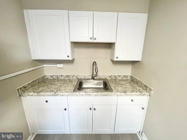 a kitchen with granite countertop white cabinets and a sink